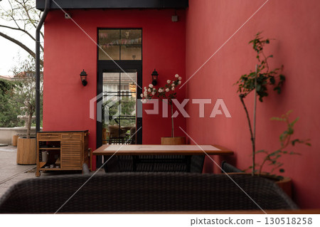 Restaurant Wall Table: Modern dining setup with red walls, plants, and furniture for a stylish atmosphere. Restaurant Wall Table: Modern dining setup with red walls, plants, and furniture for a stylish atmosphere. 130518258