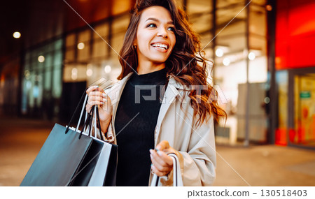 Young woman with shopping bags near mall. Spring Style. Consumerism, purchases, shopping, lifestyle Young woman with shopping bags near mall. Spring Style. Consumerism, purchases, shopping, lifestyle 130518403