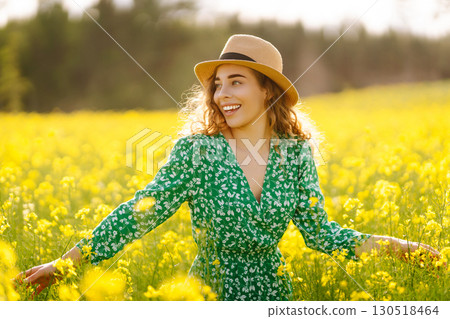 Young woman walking flowering field gently touch yellow flowers. Relax, lifestyle. Summer landscape. 130518464