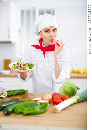 Woman chef holding salad and making bellissimo gesture Woman chef holding salad and making bellissimo gesture 130518492