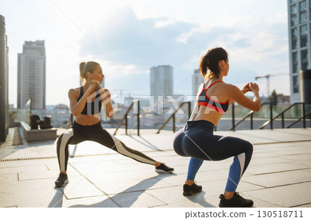 Two Young woman in sports outfit doing exercises outdoors in the morning. Sport, sports training. Two Young woman in sports outfit doing exercises outdoors in the morning. Sport, sports training. 130518711