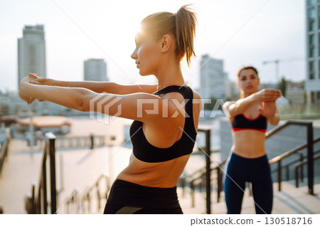 Two Young woman in sports outfit doing exercises outdoors in the morning. Sport, sports training. 130518716