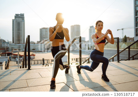 Two Young woman in sports outfit doing exercises outdoors in the morning. Sport, sports training. Two Young woman in sports outfit doing exercises outdoors in the morning. Sport, sports training. 130518717