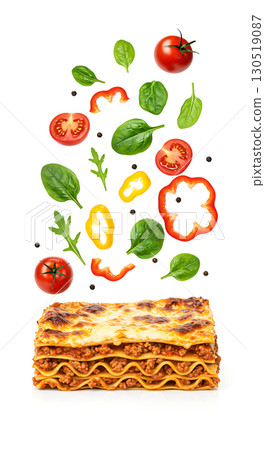 Layered pasta dish topped with melted cheese. Floating above are sliced tomatoes, bell peppers, spinach leaves, and whole peppercorns, creating a colorful and vibrant composition 130519087