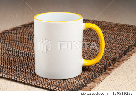 Two-tone 11oz mug on the straw mat on the table. Mug with yellow handle and inner part. Two-tone 11oz mug on the straw mat on the table. Mug with yellow handle and inner part. 130519252