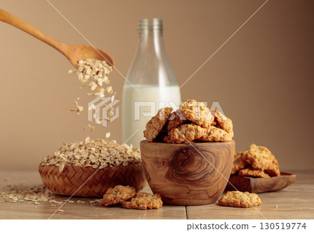 Oatmeal cookies and milk sit on a kitchen table. 130519774