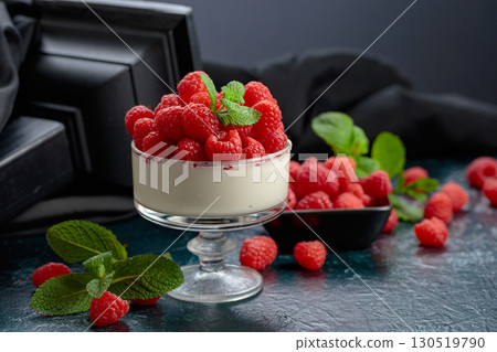 Panna cotta with fresh raspberries in a clear bowl. 130519790