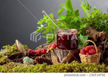 A jar of raspberry jam with fresh berries in small basket. 130519792