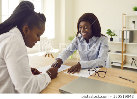 Two smiling business women working in office, reaching agreement or signing a contract. Two smiling business women working in office, reaching agreement or signing a contract. 130519848
