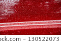 Raindrops on a vibrant red surface, showing a blurred reflection of surroundings and highlighting the beauty of nature's elements 130522073