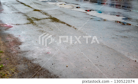 Wet pavement reflecting colors after rain, with blurred details emphasizing the rainy atmosphere 130522074