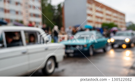 Classic car parade in rainy weather with blurred focus and crowds enjoying the event 130522082