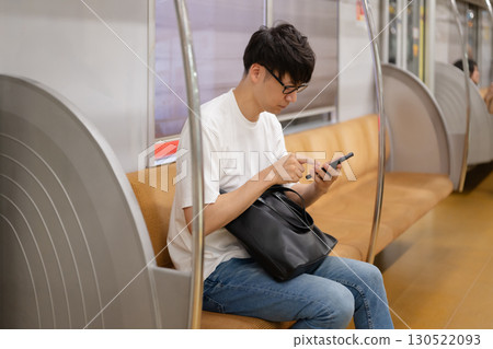 一名男子在火車上看智慧型手機 130522093