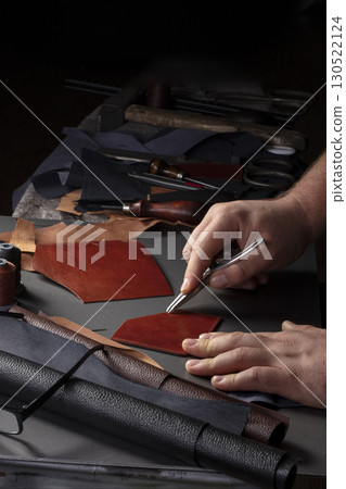 The process of making leather goods. The hands of the master work with a leather product. 130522124