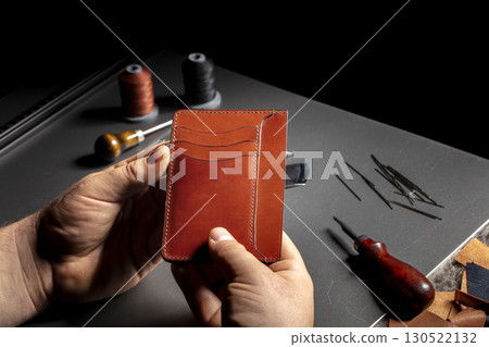 The process of making leather goods. The hands of the master work with a leather product. The process of making leather goods. The hands of the master work with a leather product. 130522132