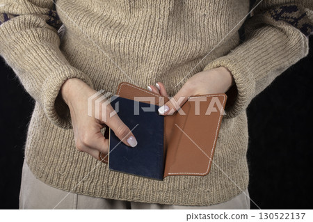 In female hands there is a brown purse and a passport. 130522137