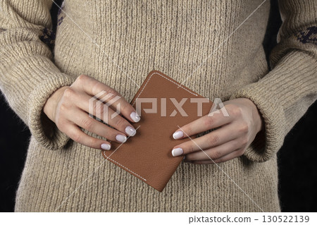 A brown leather wallet is in women's hands. 130522139