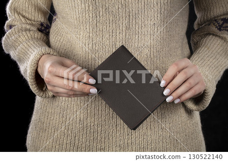 A brown leather wallet is in women's hands. A brown leather wallet is in women's hands. 130522140