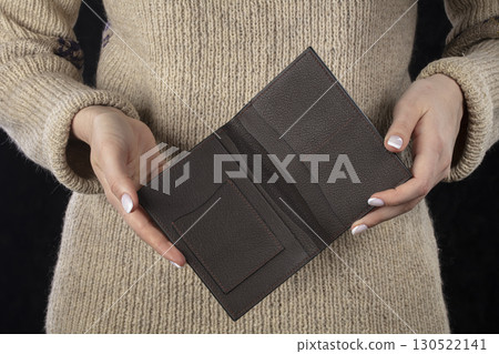 A brown leather wallet is in women's hands. A brown leather wallet is in women's hands. 130522141