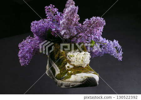 A sneaker covered with moss and blooming lavender. Shoes made from natural materials. A sneaker covered with moss and blooming lavender. Shoes made from natural materials. 130522392
