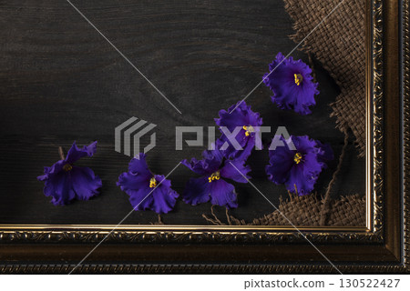 Part of a beautiful frame contains rough weave fabric on a wooden background and violet flowers. Background for the inscription. Part of a beautiful frame contains rough weave fabric on a wooden background and violet flowers. Background for the inscription. 130522427