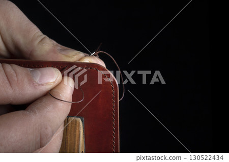 Making leather wallets. The hands of the master sew a leather product. 130522434