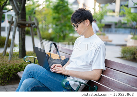 Man using a laptop on a bench Man using a laptop on a bench 130523968