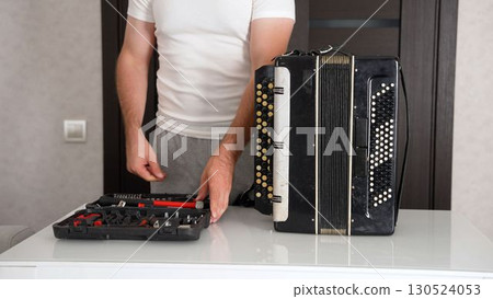 Technician repairing accordion on white table. Experienced accordion repair technician. 130524053
