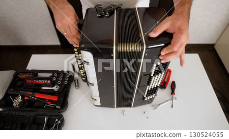 Technician repairing old accordion with screwdriver Technician repairing old accordion with screwdriver 130524055