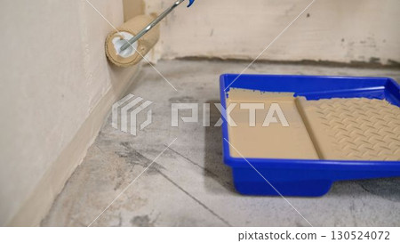 Painter dipping and applying paint with roller 130524072