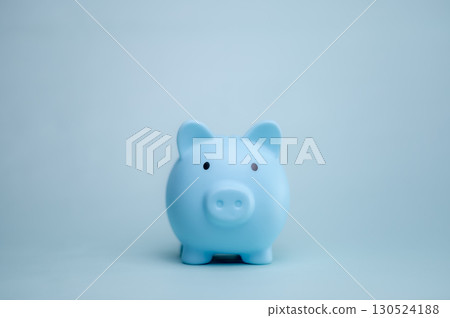 A hand is dropping coins into a piggy bank. The concept of saving and investing. 130524188