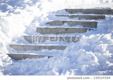 The concrete steps of the staircase are covered with white snow. 130524304