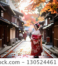 A maiko standing in the autumn leaves of the town 130524461