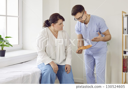 Male doctor orthopedist consulting overweight woman in medical office 130524605