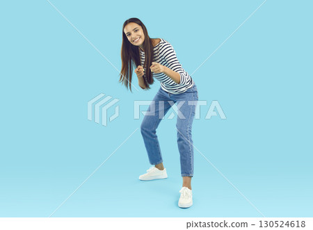 Happy young woman standing on blue studio background, pointing at you and smiling Happy young woman standing on blue studio background, pointing at you and smiling 130524618