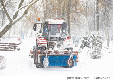 A tractor cleans the streets of the city from snow during a snowstorm. A tractor cleans the streets of the city from snow during a snowstorm. 130524736