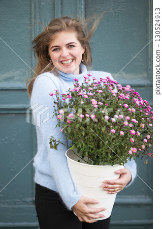 A beautiful girl is holding a large bouquet of flowers and smiling. Happy young woman in the city. A beautiful girl is holding a large bouquet of flowers and smiling. Happy young woman in the city. 130524913