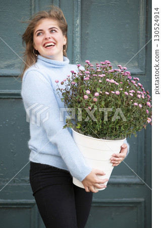 A beautiful girl is holding a large bouquet of flowers and smiling. Happy young woman in the city. 130524914