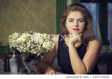 Beautiful blonde girl in a cafe at a table. Young woman in a beautiful restaurant looks at the camera. Beautiful blonde girl in a cafe at a table. Young woman in a beautiful restaurant looks at the camera. 130524920