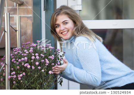 A beautiful girl is holding a large bouquet of flowers and smiling. Happy young woman in the city. A beautiful girl is holding a large bouquet of flowers and smiling. Happy young woman in the city. 130524934