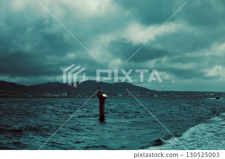 Coastal cityscape with navigation signs, rough seas and cloudy weather 130525003