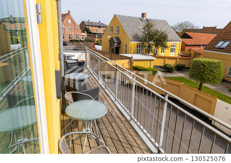 A large veranda or balcony with chairs and tables for relaxing on a summer day. 130525076