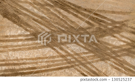 Aerial top view tire track on dirt sand mud, Texture of wet mud road with puddle and Tyre or tire track in countryside, Wheel tyre or tire track on mud, texture and background. Aerial top view tire track on dirt sand mud, Texture of wet mud road with puddle and Tyre or tire track in countryside, Wheel tyre or tire track on mud, texture and background. 130525237