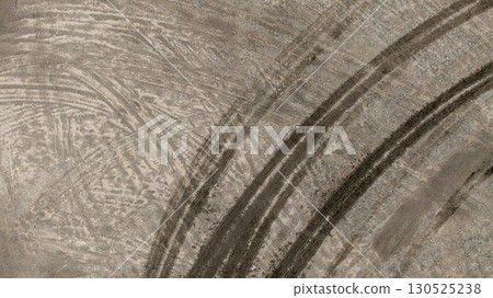 Aerial top view tire track on dirt sand mud, Texture of wet mud road with puddle and Tyre or tire track in countryside, Wheel tyre or tire track on mud, texture and background. Aerial top view tire track on dirt sand mud, Texture of wet mud road with puddle and Tyre or tire track in countryside, Wheel tyre or tire track on mud, texture and background. 130525238