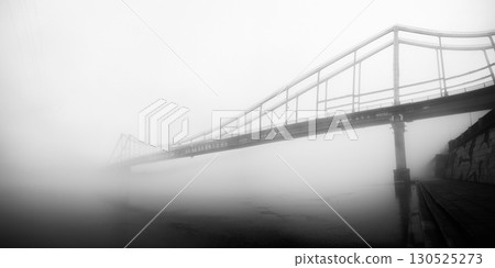 A solitary bridge emerges from the ethereal embrace of mist. 130525273