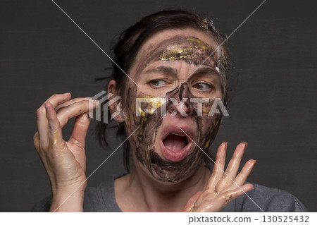 The woman removes the cosmetic mask from her face. Age-related changes in the skin in middle-aged women. The woman removes the cosmetic mask from her face. Age-related changes in the skin in middle-aged women. 130525432