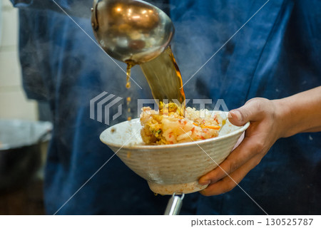立式蕎麥麵店的廚師正在將高湯淋在日式炸蕎麥面上 130525787