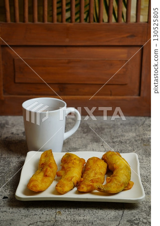 Close-up of freshly Pisang Goreng or fried Indonesian banana fritters on a white plate. A popular sweet snack or dessert. 130525805