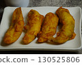 Close-up of freshly Pisang Goreng or fried Indonesian banana fritters on a white plate. A popular sweet snack or dessert. 130525806