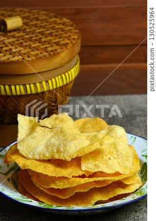 Golden and crispy opak or Indonesian Cassava Crackers on a vintage enamel plate. A popular savory snack with a crunchy texture. Golden and crispy opak or Indonesian Cassava Crackers on a vintage enamel plate. A popular savory snack with a crunchy texture. 130525964